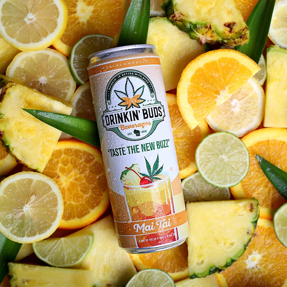 
                      
                        A chilled can of Drinkin’ Buds Mai Tai rests on a vibrant bed of sliced pineapples, oranges, limes, and lemons, highlighting its tropical and refreshing flavor.
                      
                    