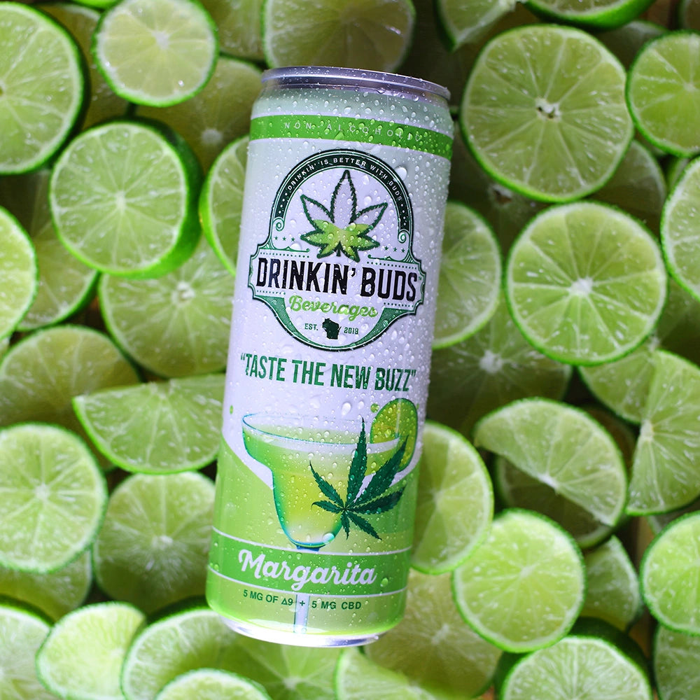
                      
                        A chilled can of Drinkin’ Buds Margarita rests on a vibrant bed of freshly sliced limes, emphasizing its citrusy and refreshing flavor.
                      
                    
