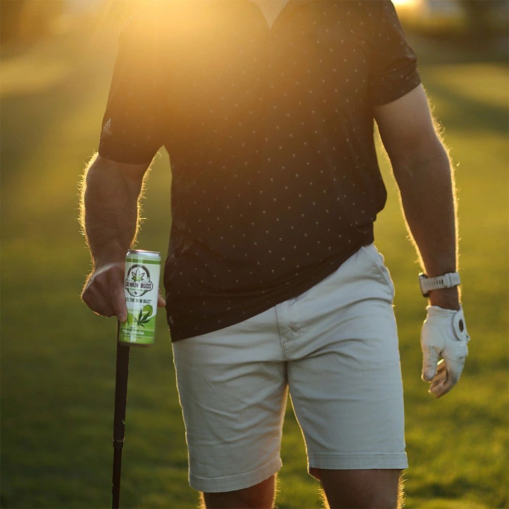 
                      
                        A golfer walks across the course at sunset, holding a can of Drinkin’ Buds Margarita in one hand and a golf club in the other, with a golf glove on his wrist.
                      
                    